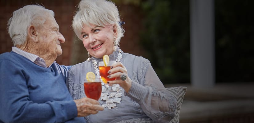 An elderly couple enjoying drinks together outdoors
