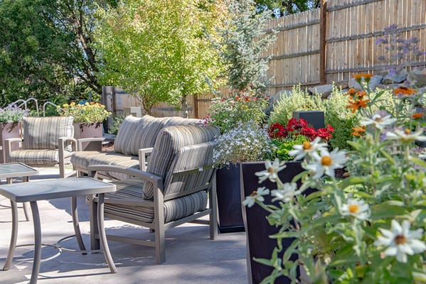 Outdoor seating area with vibrant flowers and trees
