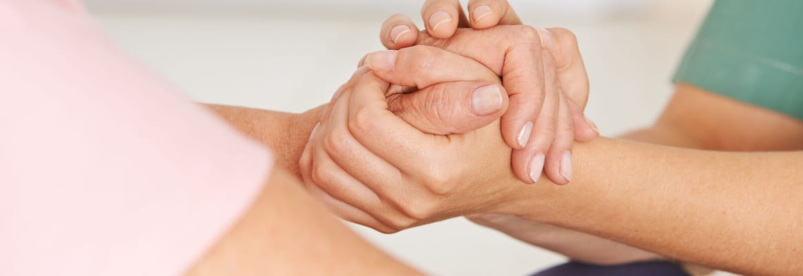 Caregiver holding a resident's hand in a gentle manner