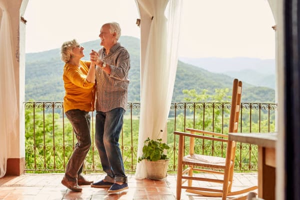 An elderly couple dancing indoors with scenic views