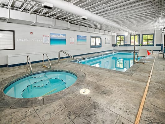 Indoor swimming pool with hot tub and lounge chairs