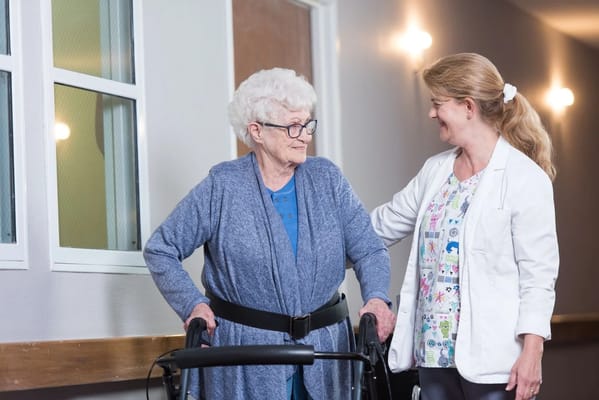 Caregiver assisting a resident in a hallway