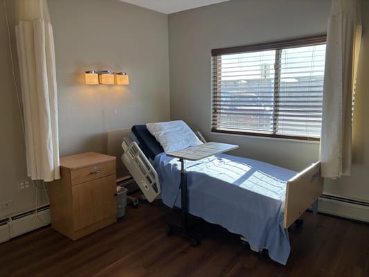 A well-lit resident room with a hospital bed