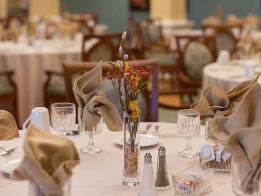 Dining area with elegantly set tables and flowers.