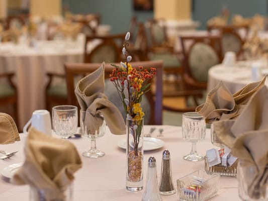 Dining area with elegantly set tables and flowers.