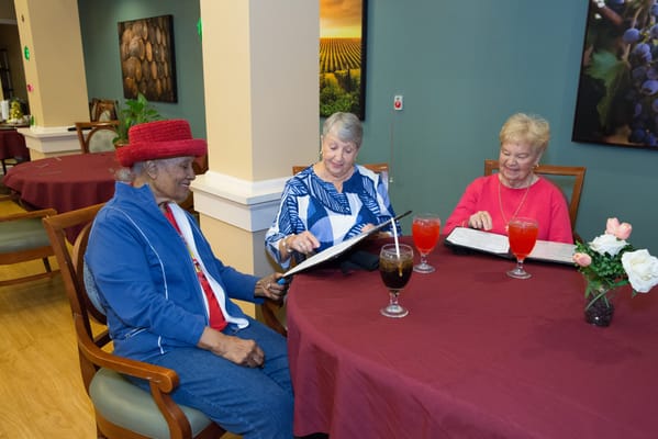 Residents enjoying drinks and reading menus in a dining area