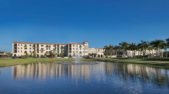Exterior view of a senior living facility by a pond