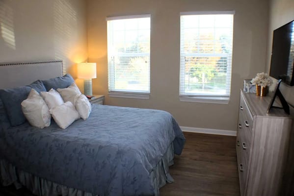 Brightly lit private resident room with a bed and window