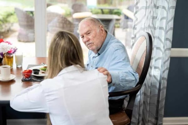 Resident enjoying a meal with staff in a dining area