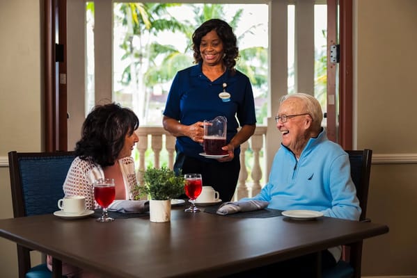 Residents enjoying drinks with a staff member in a dining area