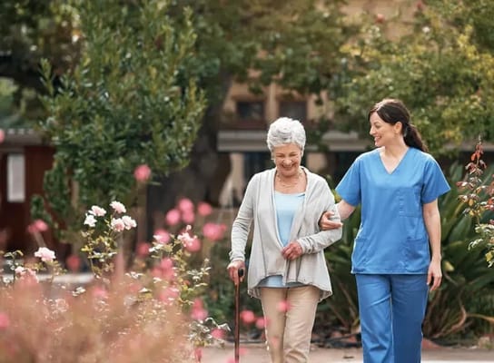 A caregiver assisting a senior outside among flowers
