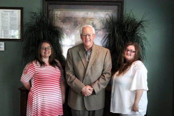 Three staff members posing together with plants in the background