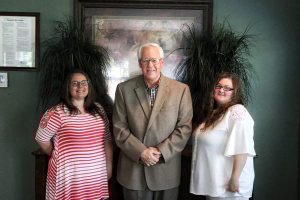 Three staff members posing together with plants in the background