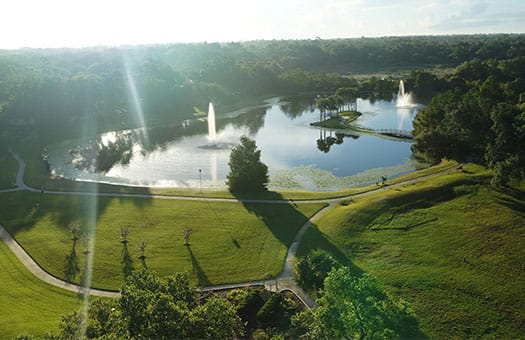 Aerial view of a serene lake with fountains and greenery