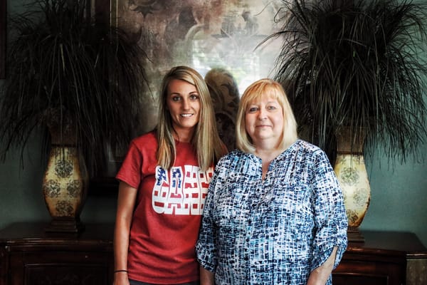 Two women posing together in a facility interior