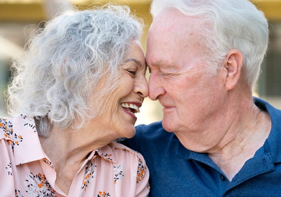 Senior couple joyfully touching foreheads outdoors