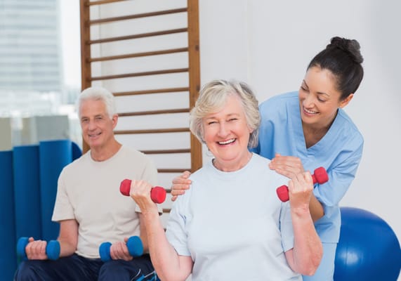 Older adults exercising with a staff member's assistance