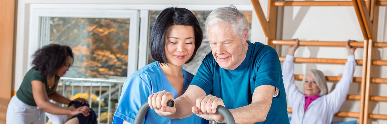 A caregiver assisting an elderly resident with exercises