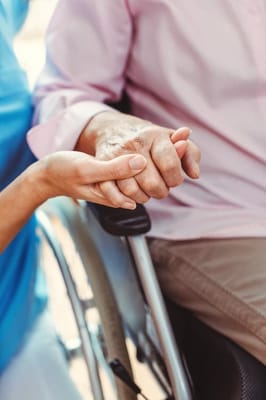 A caregiver holding hands with a resident in a wheelchair