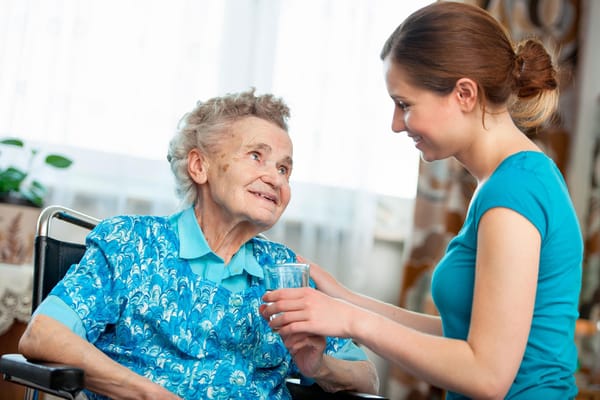 A caregiver assisting a resident with a glass of water