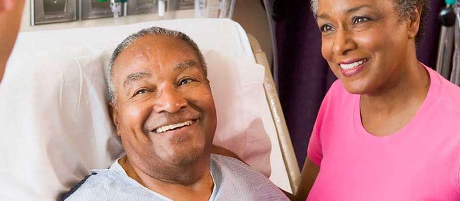 A smiling senior man with a caregiver in a facility room