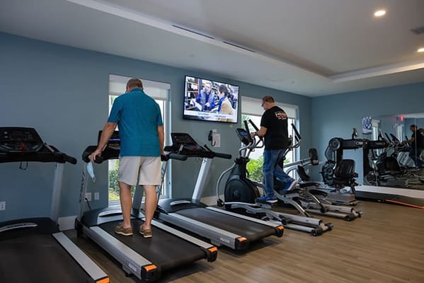Residents using fitness equipment in a gym