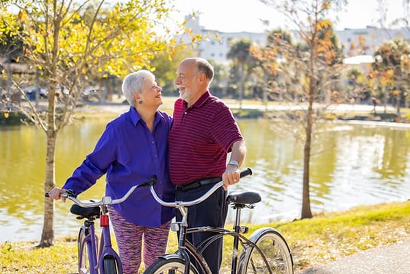 A senior couple smiling by a lake with bicycles