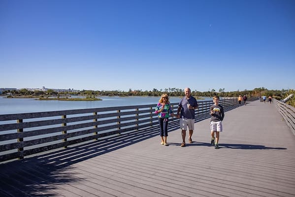 People walking along a scenic boardwalk by a lake