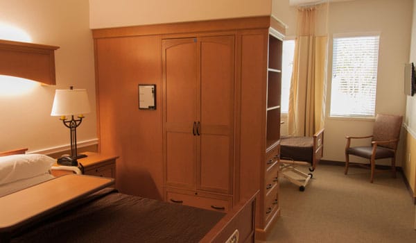 A private resident room with wooden furniture and a sunny window