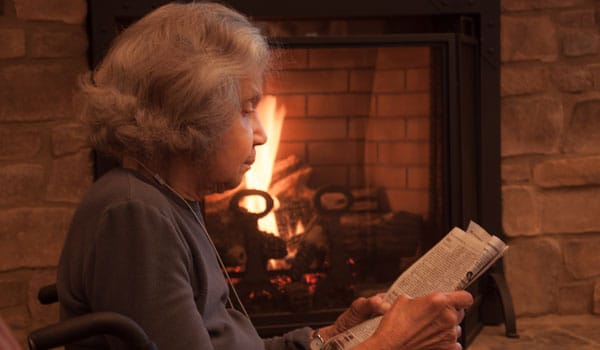 Resident reading by the fireplace in a cozy setting