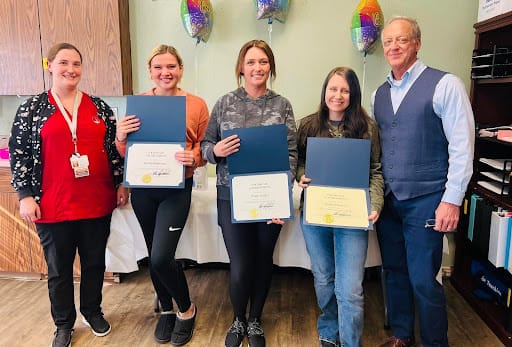 Staff members celebrating with certificates in the common area