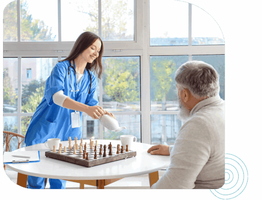 Staff member serving tea to a resident during a game of chess