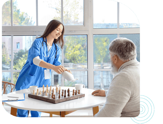Staff member serving tea to a resident during a game of chess