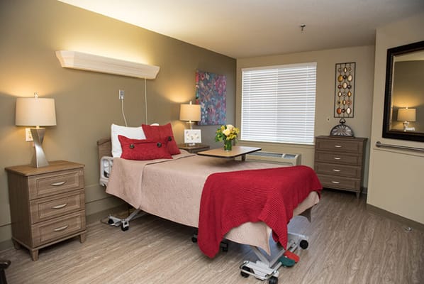 A well-decorated private resident room with a bed and lamps