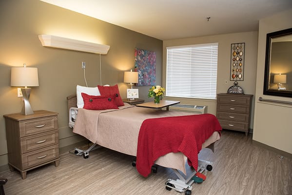 A well-decorated private resident room with a bed and lamps