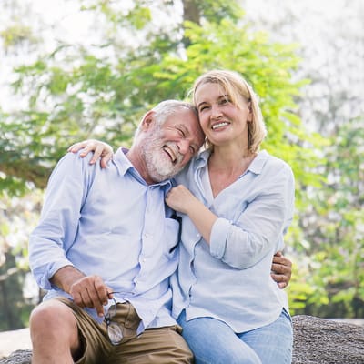 Two smiling seniors enjoying a sunny outdoor setting