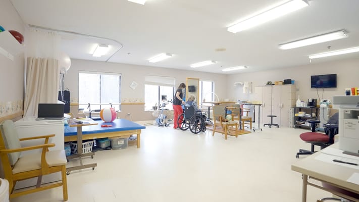 Therapy room with staff assisting a resident