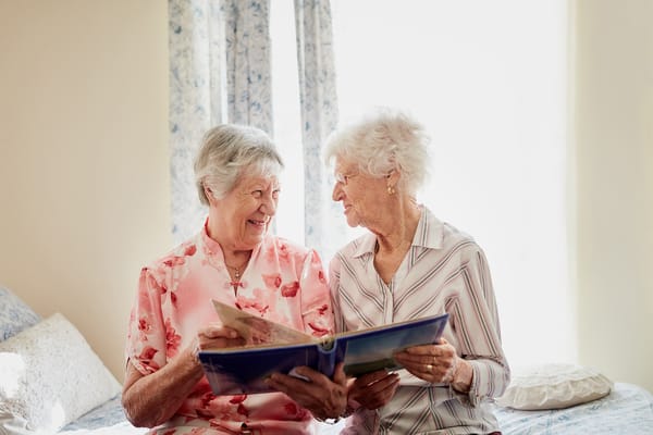 Two residents sharing a memory book in a cozy room