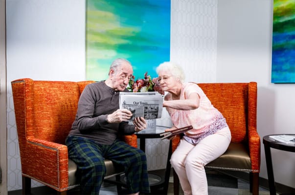 Two residents reading a newspaper in a cozy lounge
