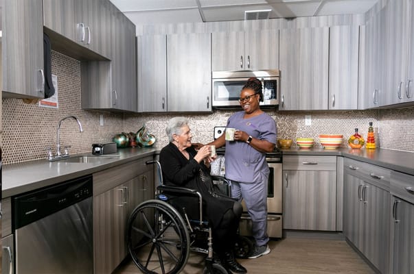 Staff assisting a resident in a modern kitchen