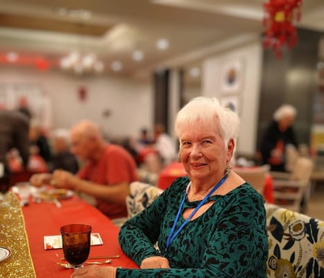 Resident smiling at a dinner table in a communal dining area