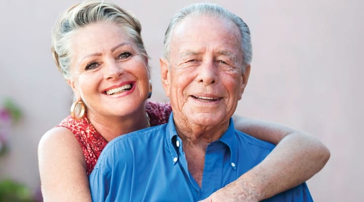 A smiling senior couple posing together outdoors