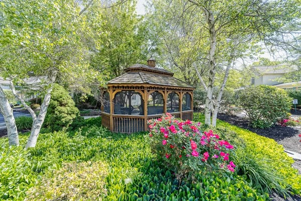 A gazebo surrounded by colorful flowers and greenery