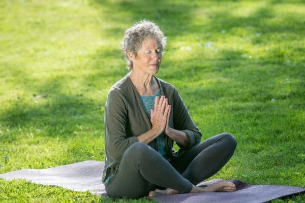 Resident practicing yoga in a green outdoor area