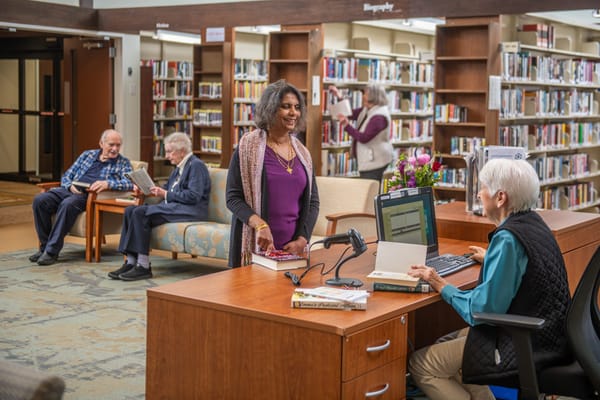 Residents and staff in a library area engaging with books