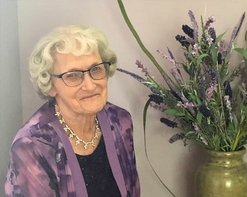 Resident smiling next to a decorative flower arrangement