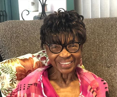 An elderly woman smiling in a cozy living room setting