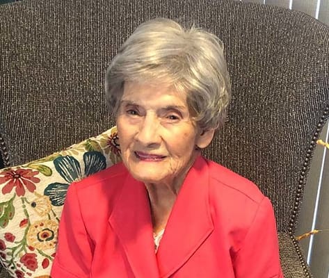 A smiling resident in a bright outfit sitting on a chair