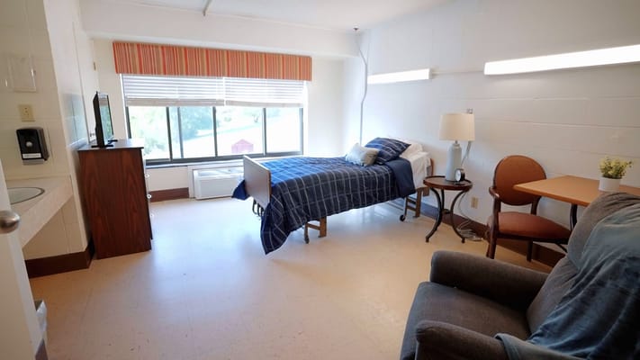 A private resident room featuring a bed and sitting area