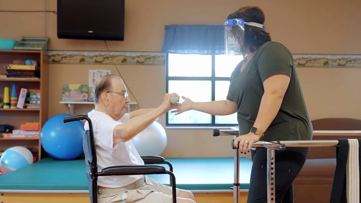 Therapist assisting a resident with a rehabilitation exercise